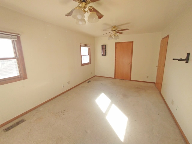 empty room with a healthy amount of sunlight, light colored carpet, and ceiling fan