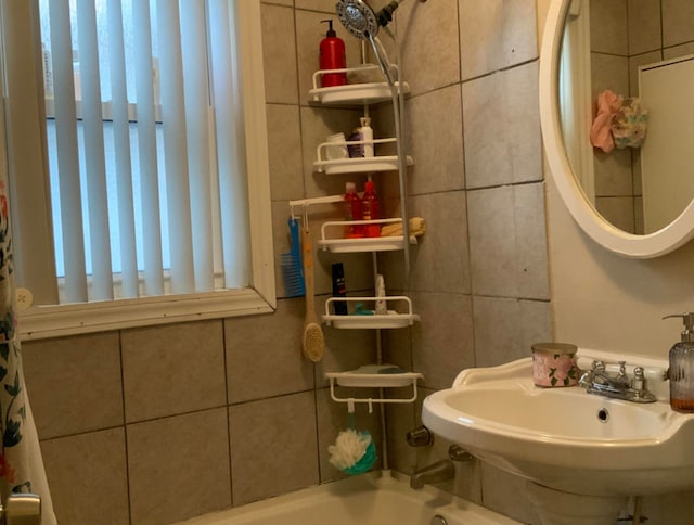 bathroom with tile walls, sink, and shower / bath combination with curtain