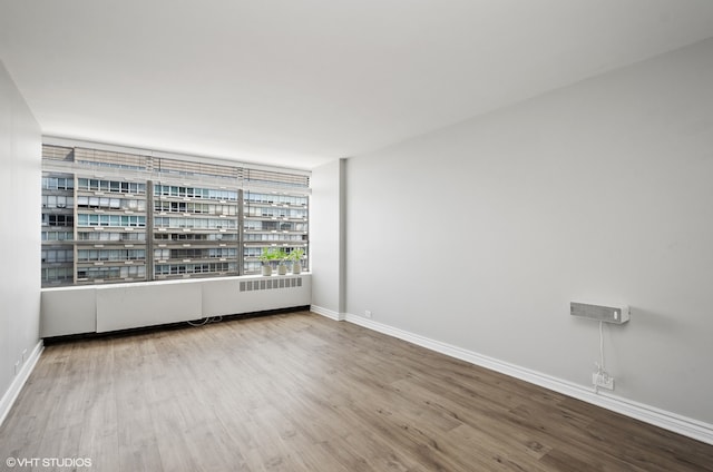 spare room with radiator heating unit and wood-type flooring