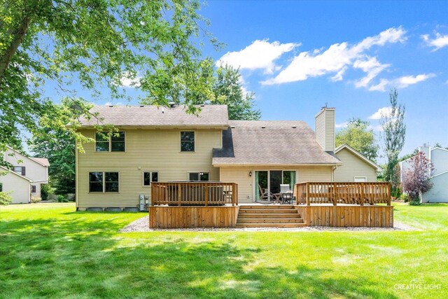 rear view of property with a deck, a yard, and a chimney