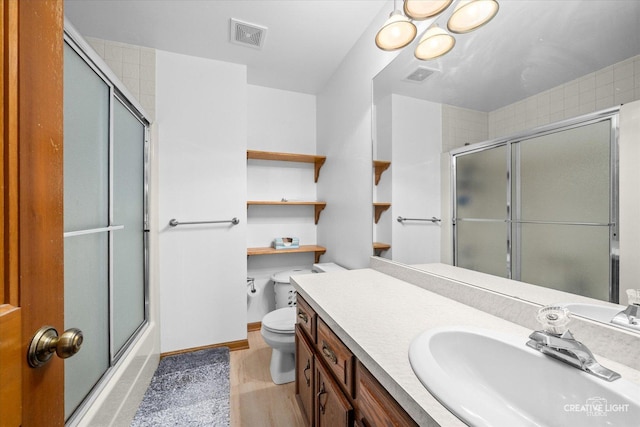 bathroom with vanity, toilet, wood finished floors, and visible vents