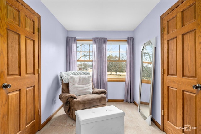 living area featuring light colored carpet and baseboards