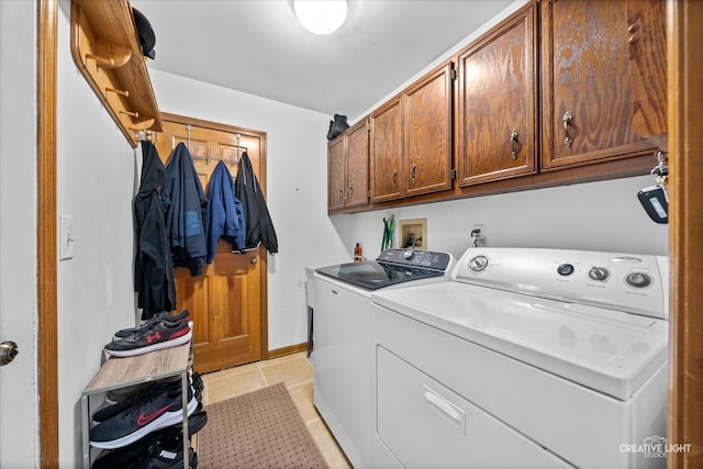 washroom featuring baseboards, cabinet space, light tile patterned flooring, and washer and clothes dryer