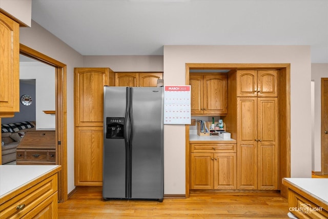 kitchen featuring light countertops, brown cabinetry, stainless steel fridge with ice dispenser, and light wood-type flooring