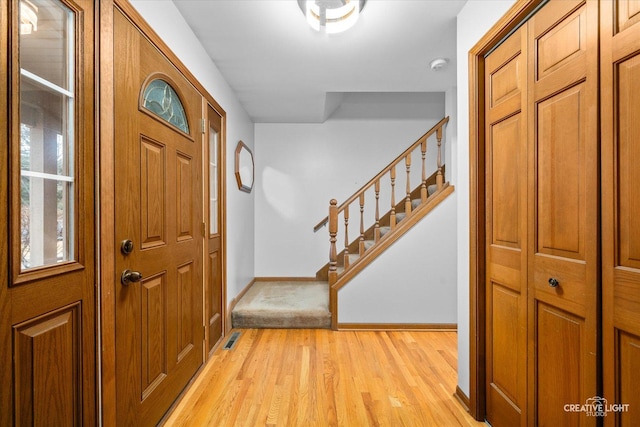 entryway with visible vents, light wood-style flooring, stairs, and baseboards