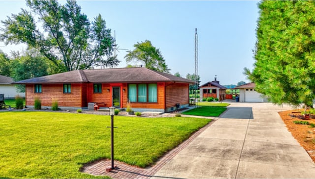 view of front facade with a detached garage, a front lawn, and an outbuilding