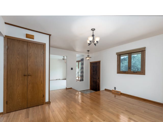 unfurnished room with a chandelier and light wood finished floors