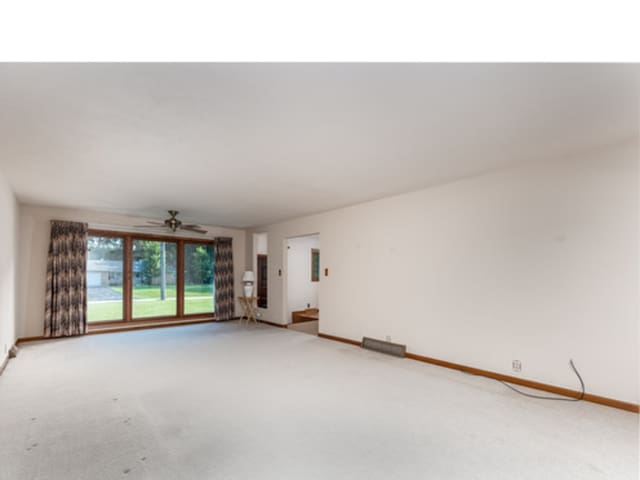 spare room with baseboards, ceiling fan, and light colored carpet