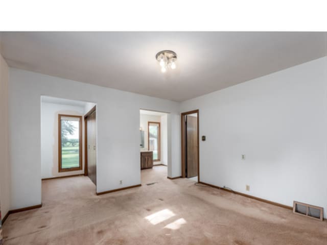 empty room featuring light carpet, baseboards, and visible vents