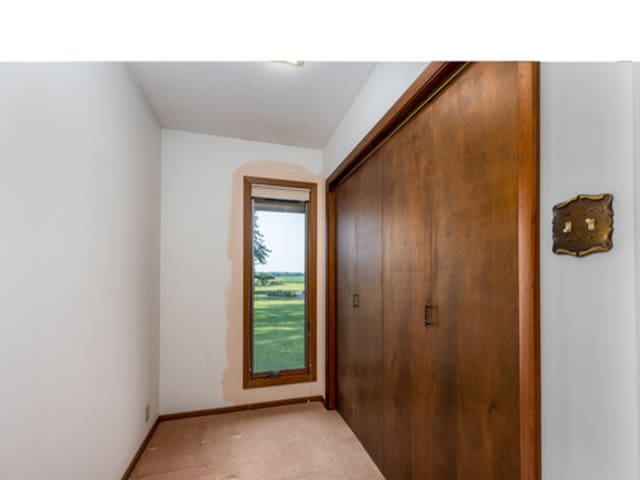 doorway to outside with baseboards and light colored carpet