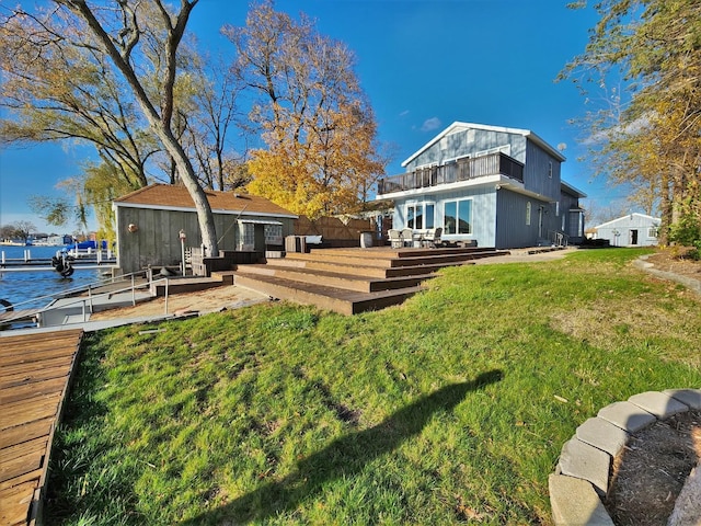 rear view of house with a yard and a deck with water view