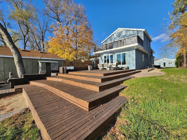 rear view of property featuring outdoor dining area, a lawn, and a deck