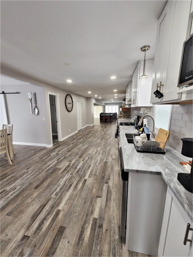 kitchen featuring light stone counters, white cabinets, wood finished floors, and decorative light fixtures