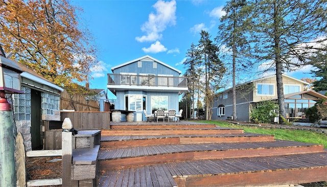 rear view of property featuring a balcony and a wooden deck