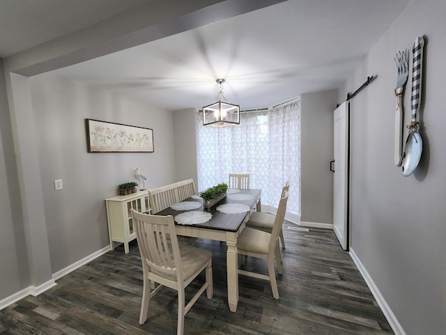 dining area featuring dark wood-type flooring, a chandelier, and a barn door