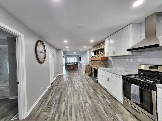 kitchen with wall chimney range hood, backsplash, pool table, stainless steel gas range, and hardwood / wood-style flooring