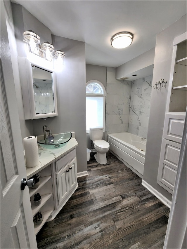 full bathroom with vanity, toilet, tiled shower / bath, and hardwood / wood-style floors