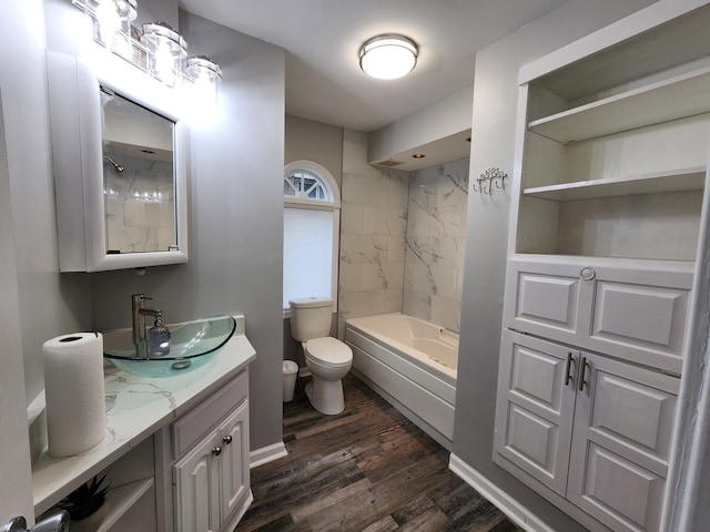 full bathroom with vanity, toilet, tiled shower / bath, and hardwood / wood-style floors