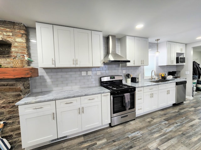 kitchen with dark wood-type flooring, white cabinets, stainless steel appliances, and wall chimney exhaust hood