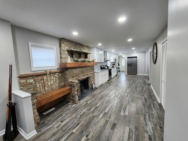 living room with a stone fireplace and dark hardwood / wood-style floors