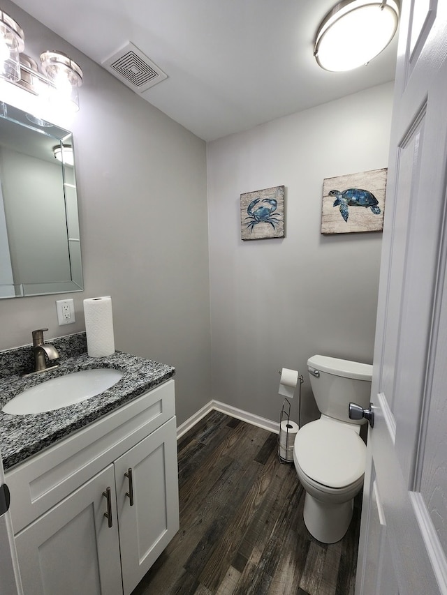 bathroom with toilet, hardwood / wood-style floors, and vanity