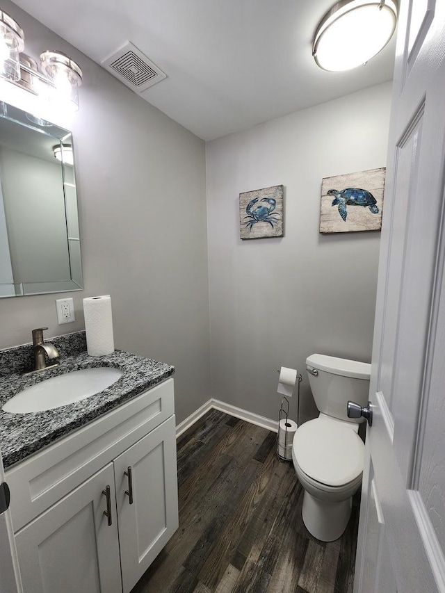 bathroom with visible vents, toilet, vanity, wood finished floors, and baseboards