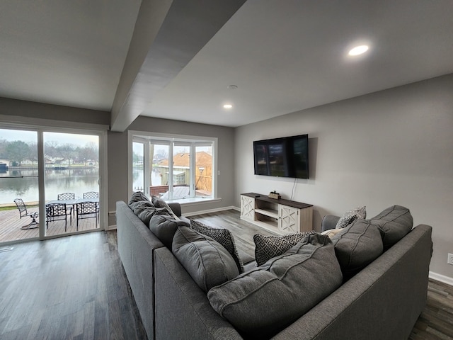 living room featuring a water view, beamed ceiling, and hardwood / wood-style flooring