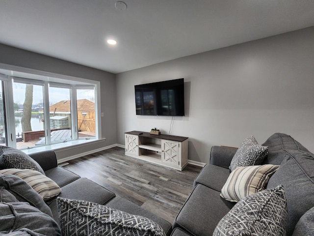 living room featuring recessed lighting, a water view, dark wood finished floors, and baseboards