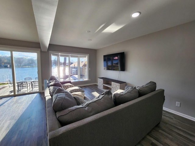 living room featuring a water view, dark wood finished floors, and baseboards