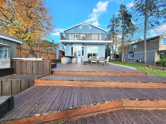 back of house with a deck, fence, and a balcony