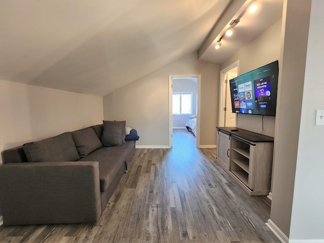 living room with track lighting, vaulted ceiling, baseboards, and wood finished floors