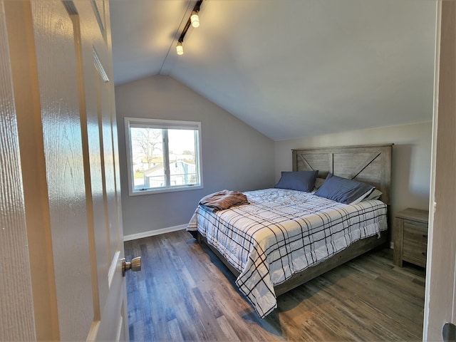 bedroom featuring dark wood-type flooring, vaulted ceiling, and rail lighting