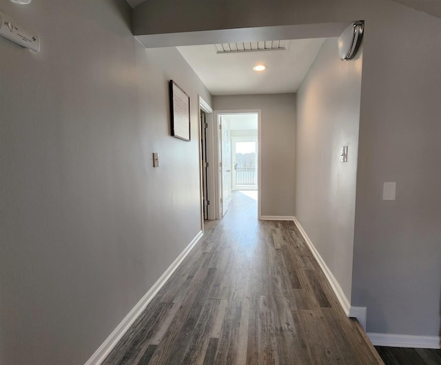 hallway with dark wood-style flooring, visible vents, and baseboards