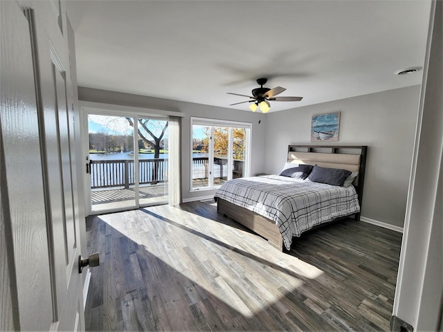 bedroom with visible vents, baseboards, dark wood-style flooring, a water view, and access to outside