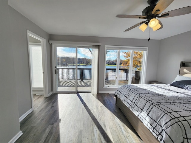 bedroom featuring dark wood-style flooring, a water view, ceiling fan, access to outside, and baseboards