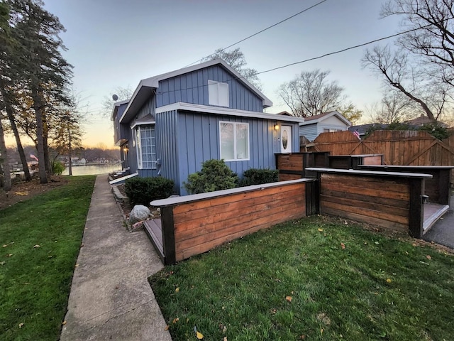 exterior space featuring board and batten siding, fence, a lawn, and exterior bar