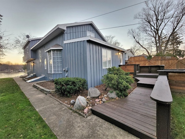 view of side of home with board and batten siding, fence, and a wooden deck