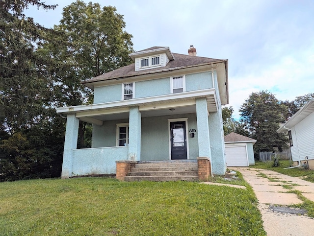 view of front facade with an outbuilding, covered porch, a front yard, and a garage