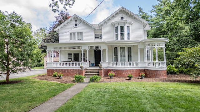 victorian house featuring covered porch and a front yard