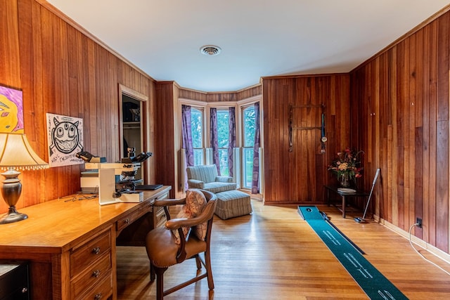 office featuring light hardwood / wood-style flooring, ornamental molding, and wooden walls