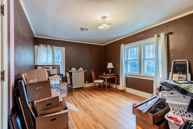 miscellaneous room with radiator, crown molding, and light hardwood / wood-style flooring