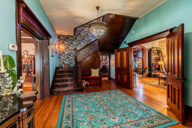 entrance foyer featuring wood-type flooring, vaulted ceiling, and a notable chandelier