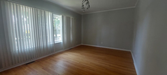 spare room with a wealth of natural light, crown molding, and hardwood / wood-style floors