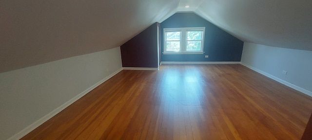 additional living space featuring wood-type flooring and vaulted ceiling