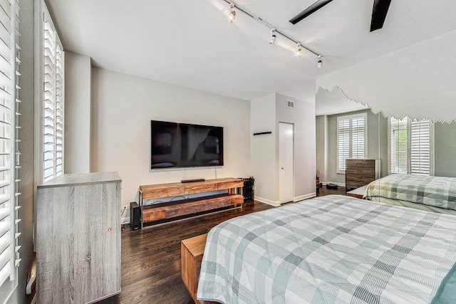 bedroom with ceiling fan, dark hardwood / wood-style flooring, and track lighting