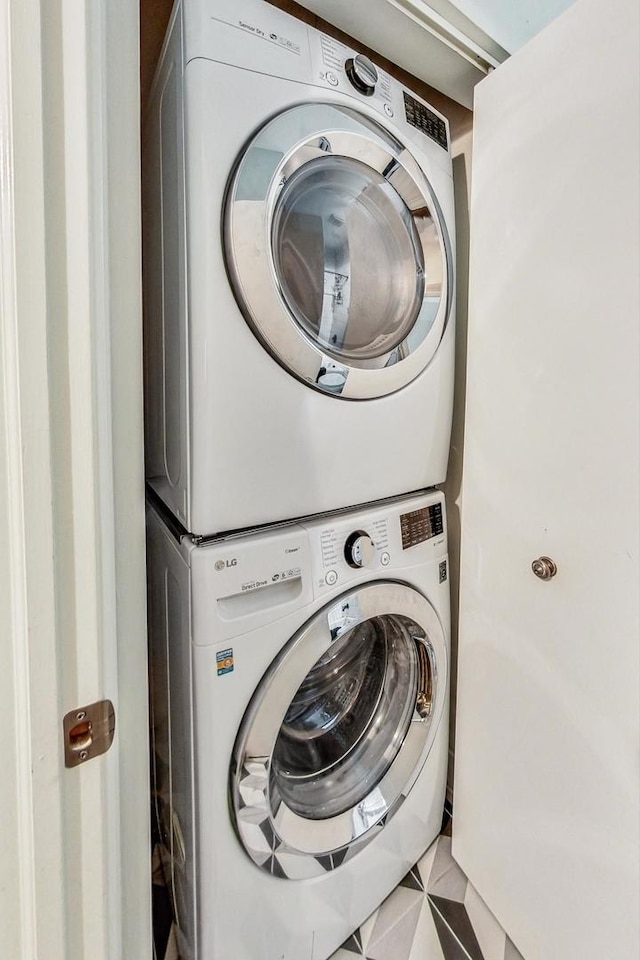 clothes washing area featuring light tile patterned floors and stacked washer / dryer