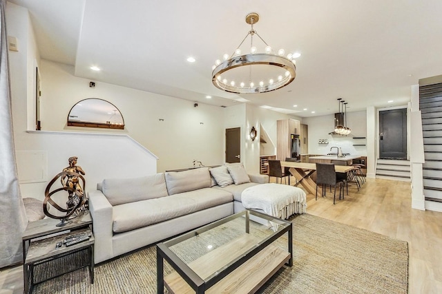 living room with a chandelier, light hardwood / wood-style flooring, and sink