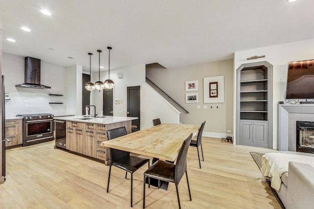 dining area with built in shelves, light wood-type flooring, and sink