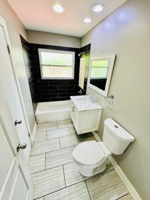 bathroom featuring baseboards, shower / bathing tub combination, vanity, and toilet