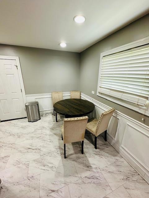 dining area featuring a wainscoted wall, marble finish floor, and recessed lighting